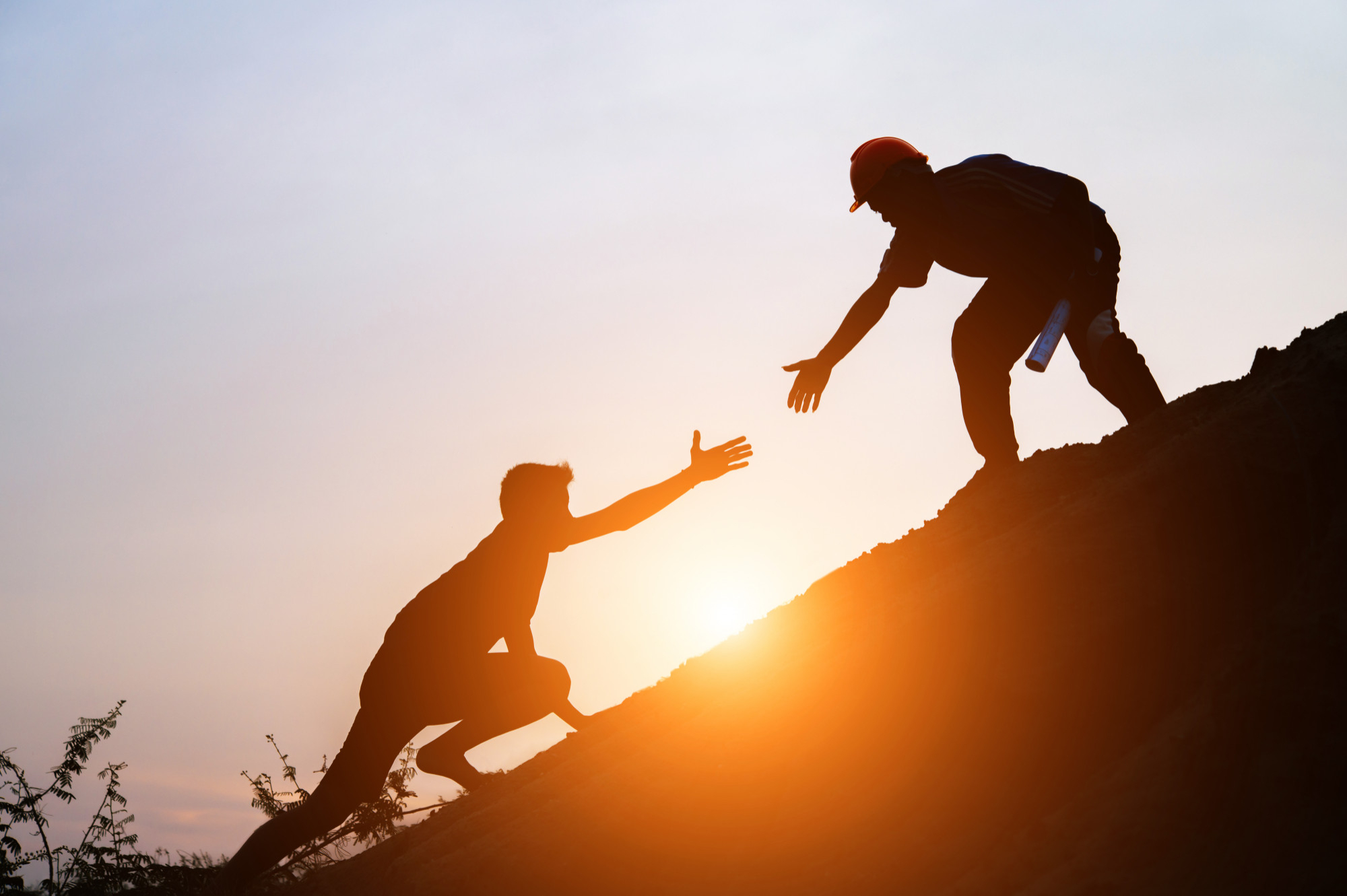 A man lending a hand to another on a steep pathway