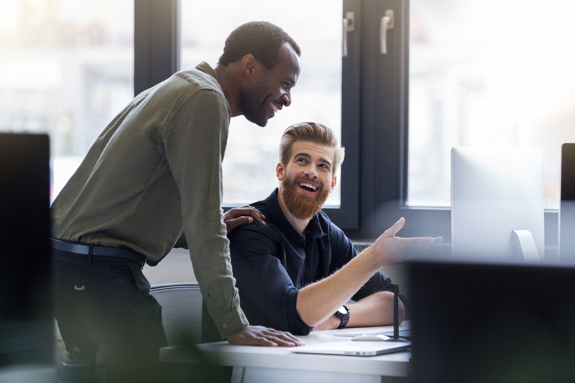 Two guys smiling as one shows off something on a computer screen