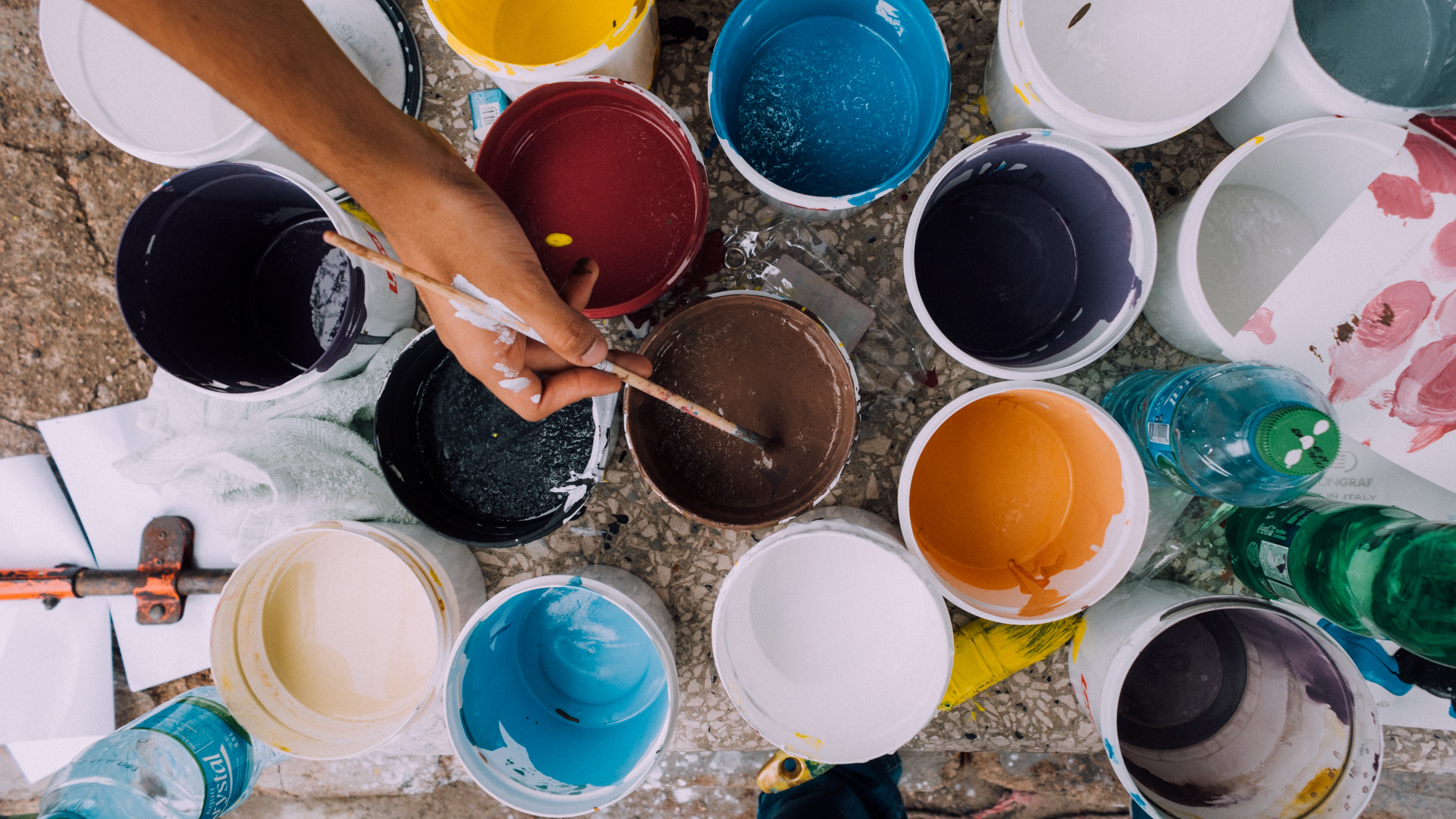 Oil paint buckets with paint brush dipped in brown oil paint