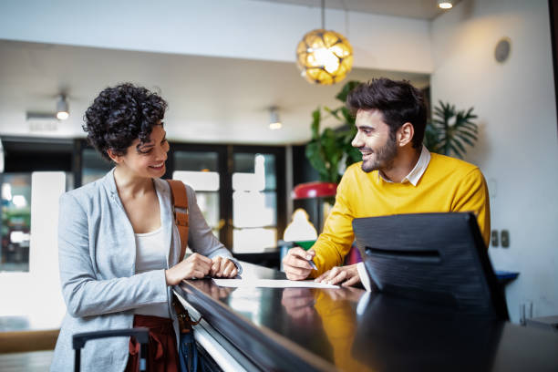 A businesswoman and a hotel concierge talking happily at the front desk