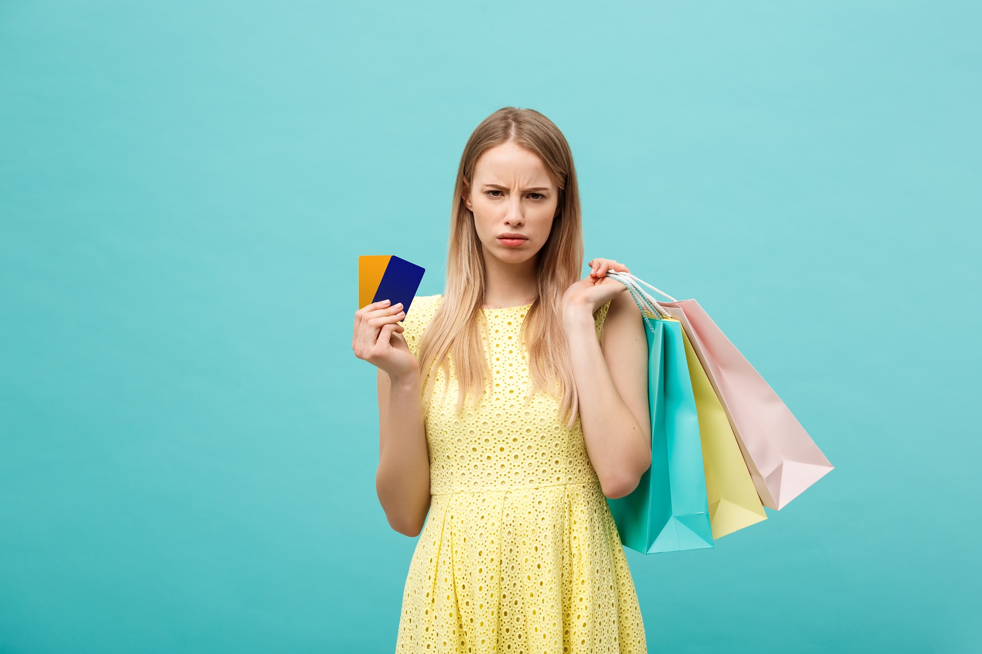 A woman holding credit cards with and shopping bags and frowning