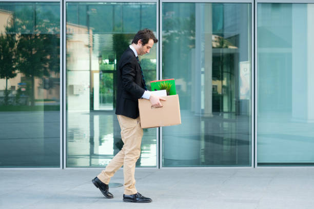 A man walking out of the office with his stuff packed in a box