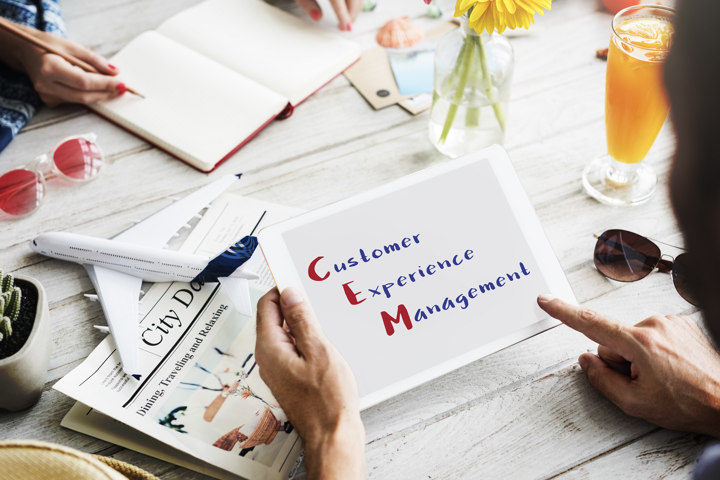 Hand holding a tablet with 'Customer Experience Management' displayed on it