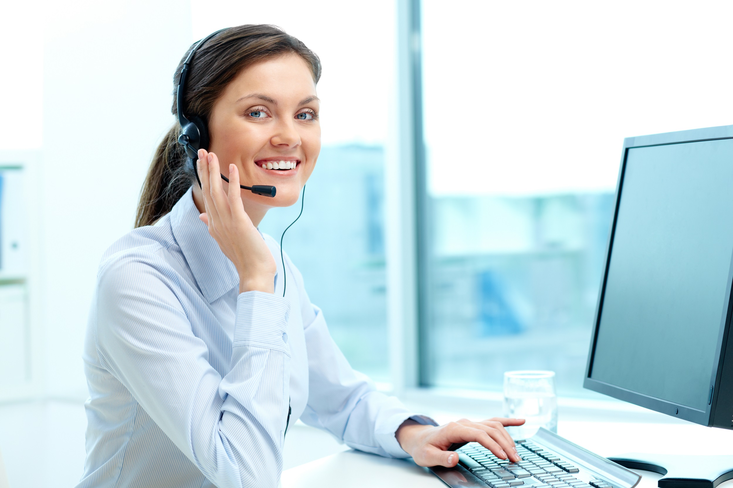 Customer service representative wearing a headset and sitting in front of a PC