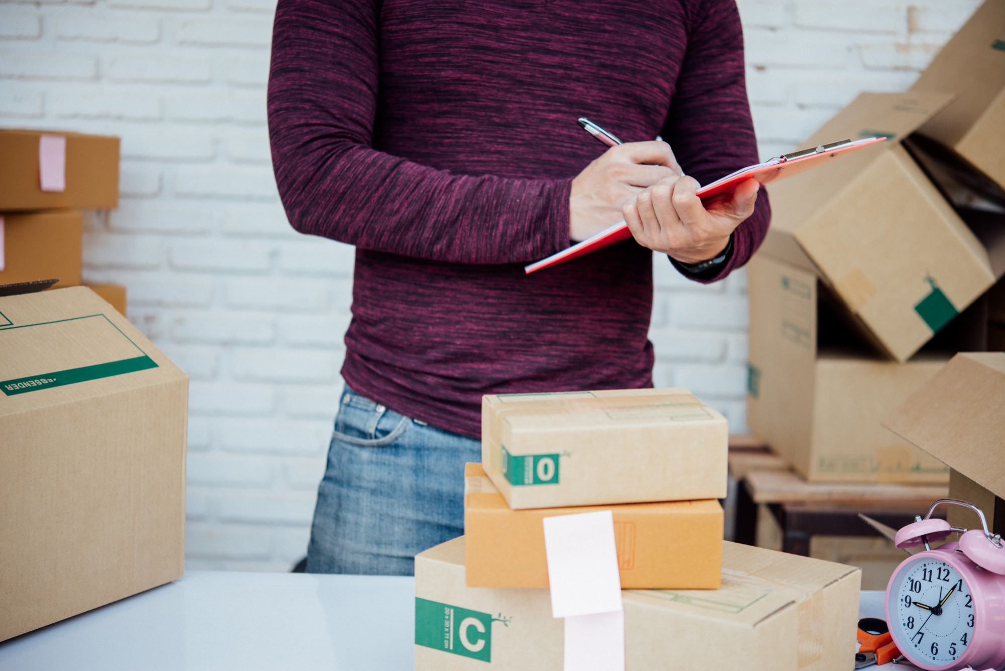 A man in a warehouse, taking notes on a clipboard