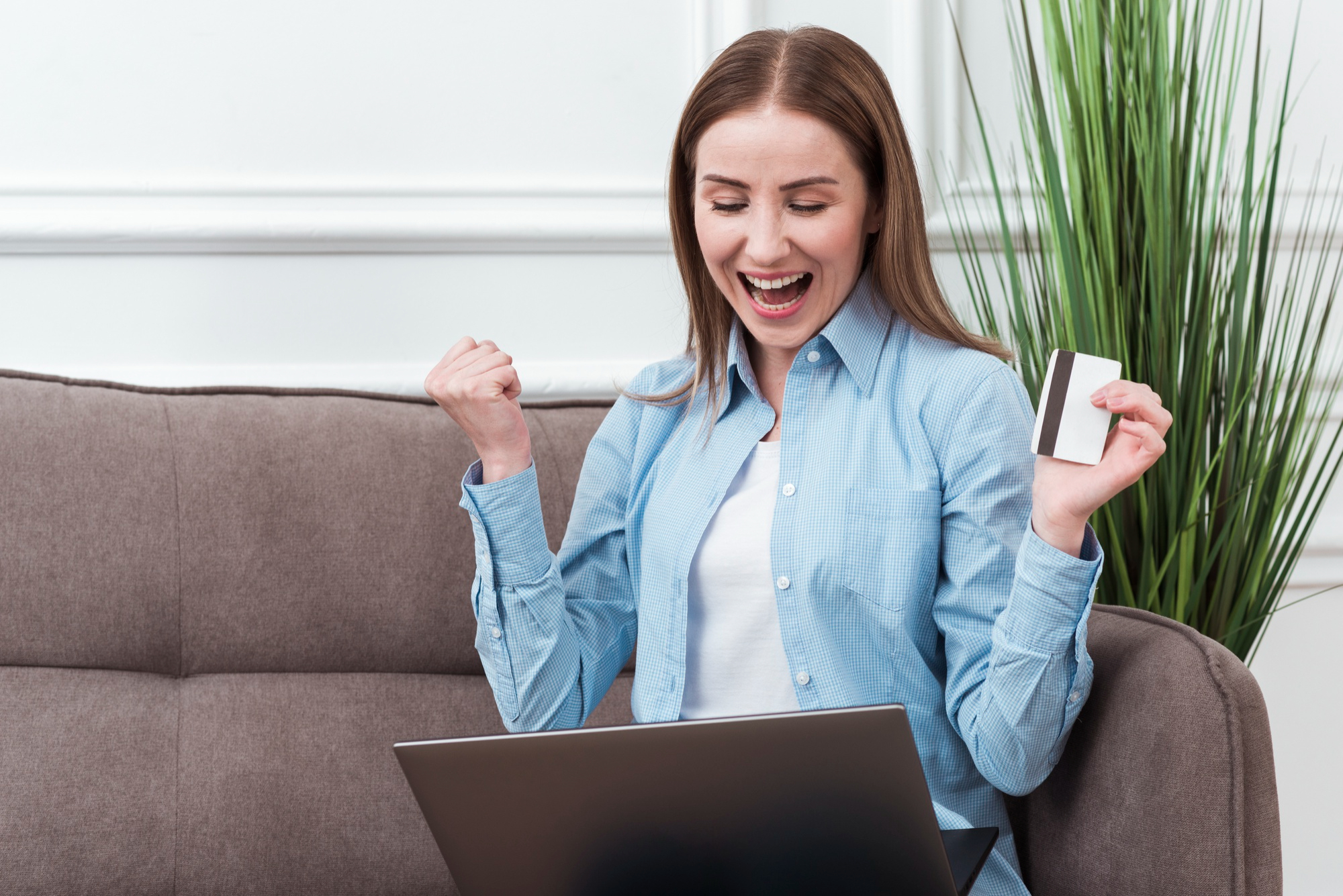 Exhilarated online shopper with a credit card in her hand