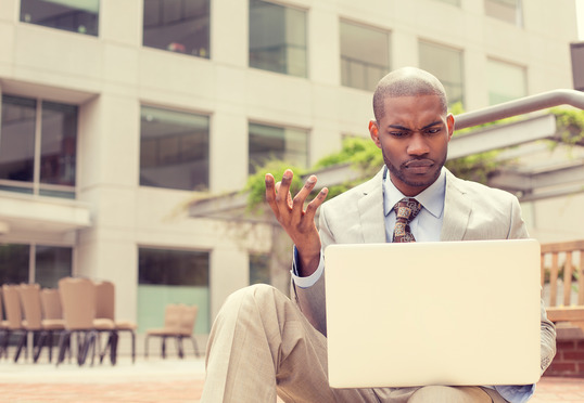 A perplexed businessman looking at his laptop