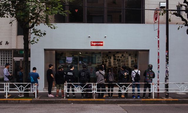 Men Waiting in Line Outside a Store