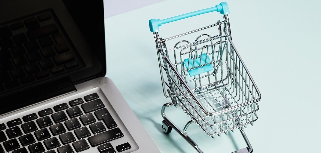 Miniature shopping cart beside laptop