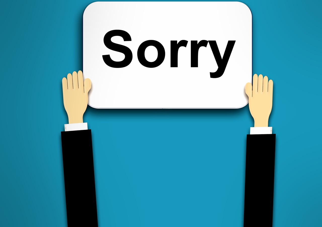 Businessperson Holding Up Sorry Sign